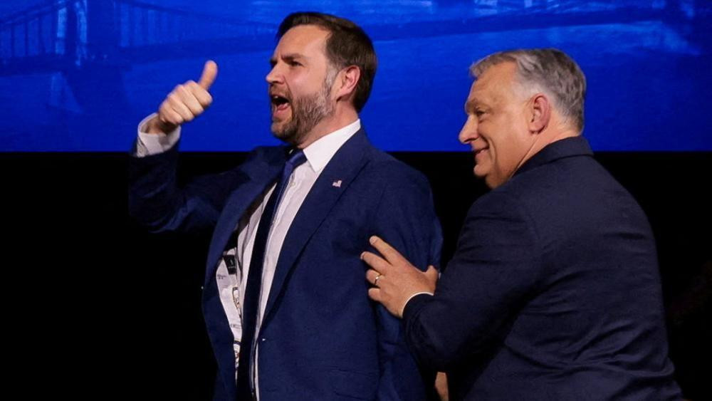 Vens drži palac u vazduhu dok ga Orban gura u leđa sa desne strane 