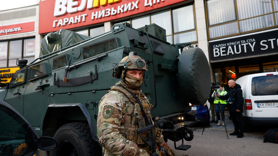 A Rapid Operational Response Unit member stands by an armoured vehicle outside a supermarket