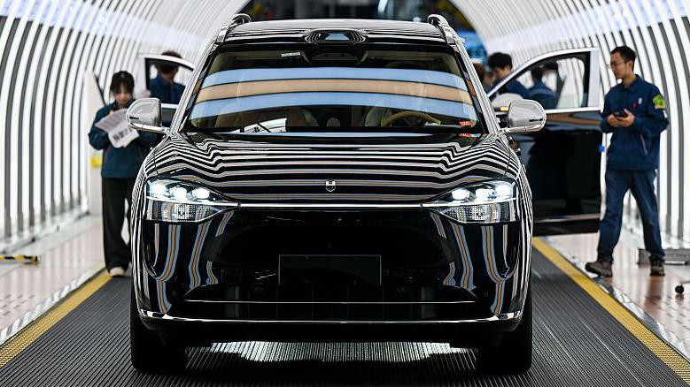 crni automobil sa otvorenim vratima i nekoliko ljudi u radnim odelima