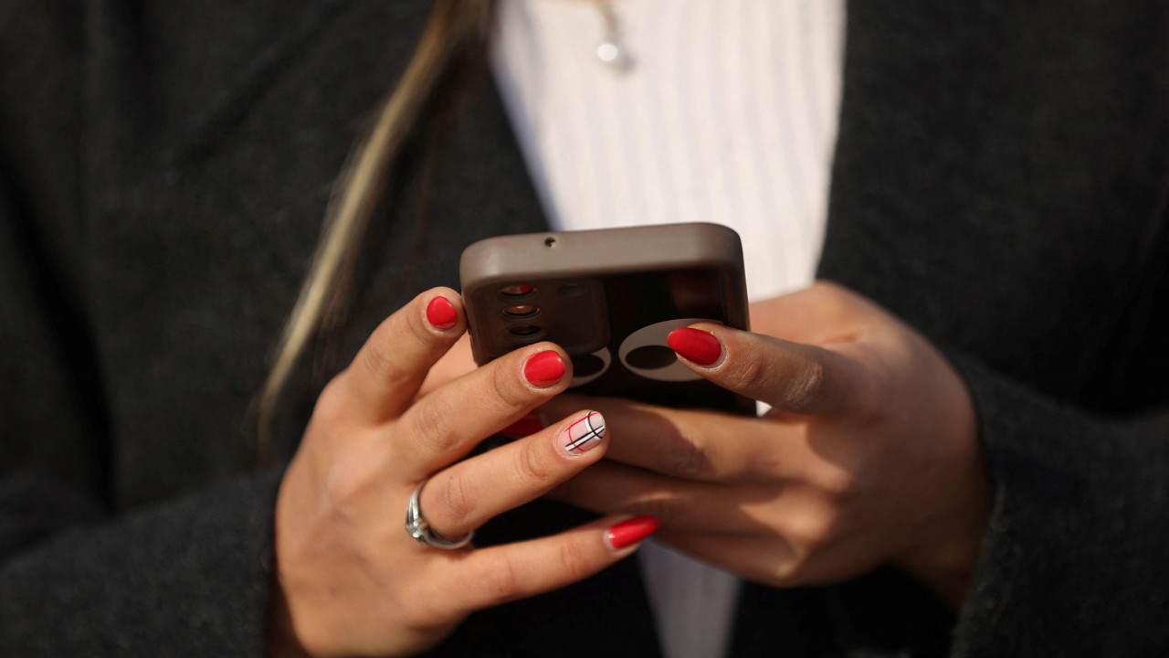mobilni telefon u rukama žene sa nalakiranim noktima