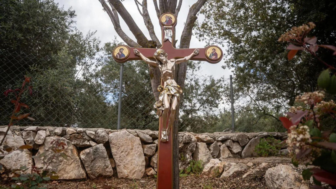 Zlatna statua Isusa na drvenom krstu u prirodi