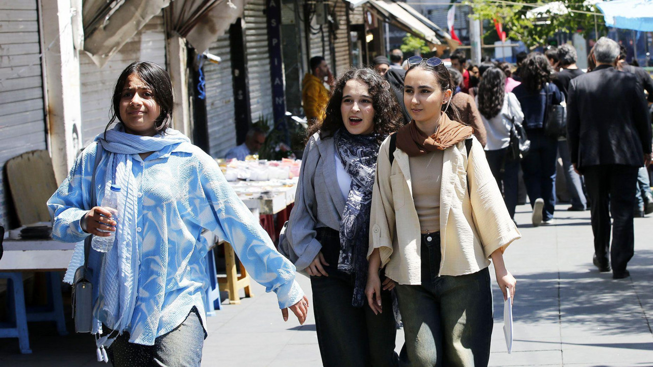 Young women walking down a busy shopping street in Tehran