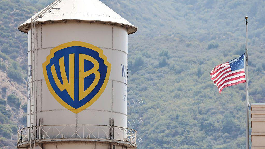 A water silo with the Warner Bros logo on it next to a US flag.
