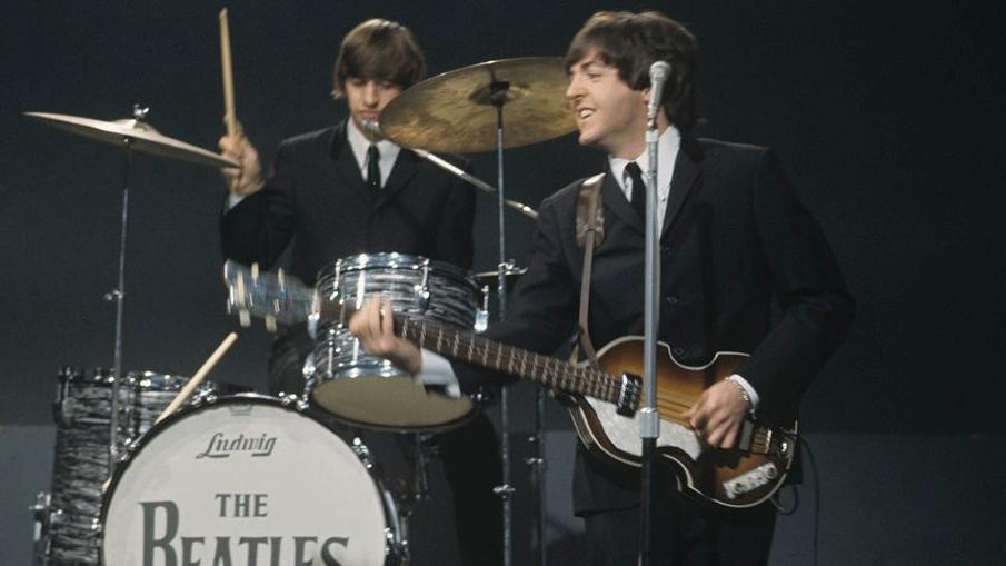 Ringo Star svira bubnjeve iza , basiste i pevača Pola Makartnija 1964. godine.
