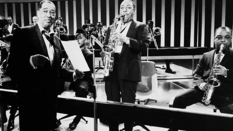 Djuk Elington u smokingu oko njega nekoliko članova orkestra