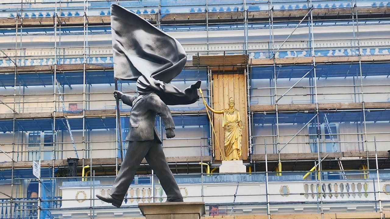 Statua je postavljena ispred pozlaćene biste boginje Atine na fasadi čuvenog kluba Atenaeum