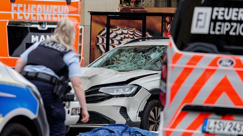 a police officer in front of a damaged car