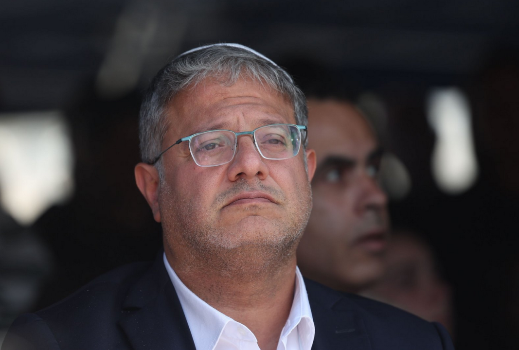 Portret izraelskog ministra sa naočalama dok gleda u daljinu, ima belu košulju i crni sako