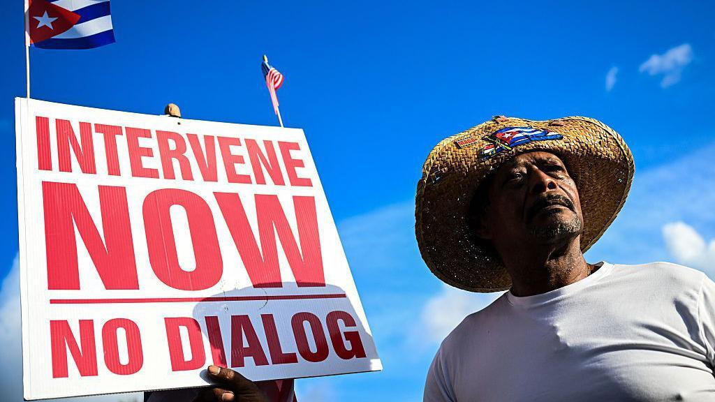 Man holding an "intervene now" sign in Miami, Florida. 