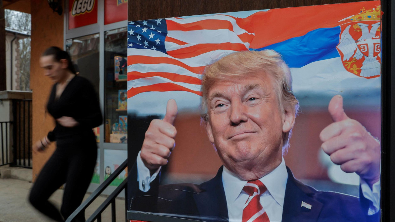 Devojka u Severnoj Mitrovici prolazi pored postera sa Donaldom Trampom i zastavama Srbije i Sjedinjenih Američkih Država 