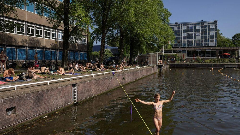 vrućina u amsterdamu, devojka hoda po živi iznad kanala u amsterdamu