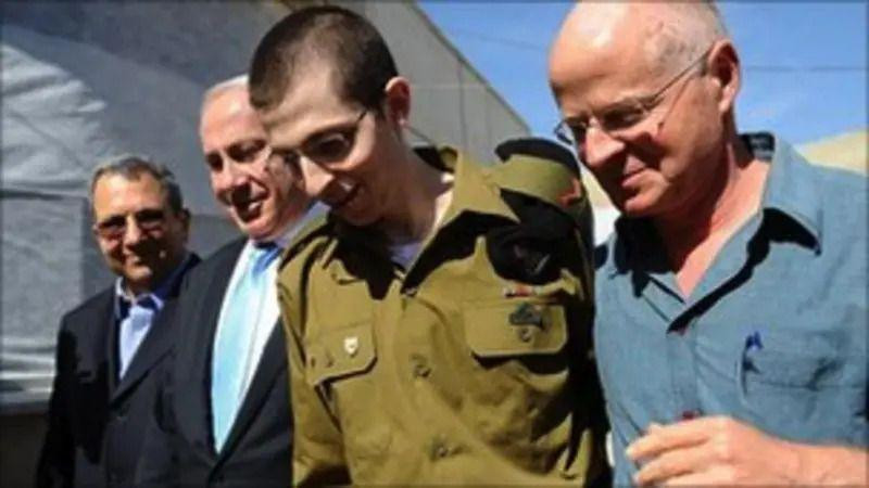 Mladić u zelenoj uniformi sa trojicom starijih muškaraca