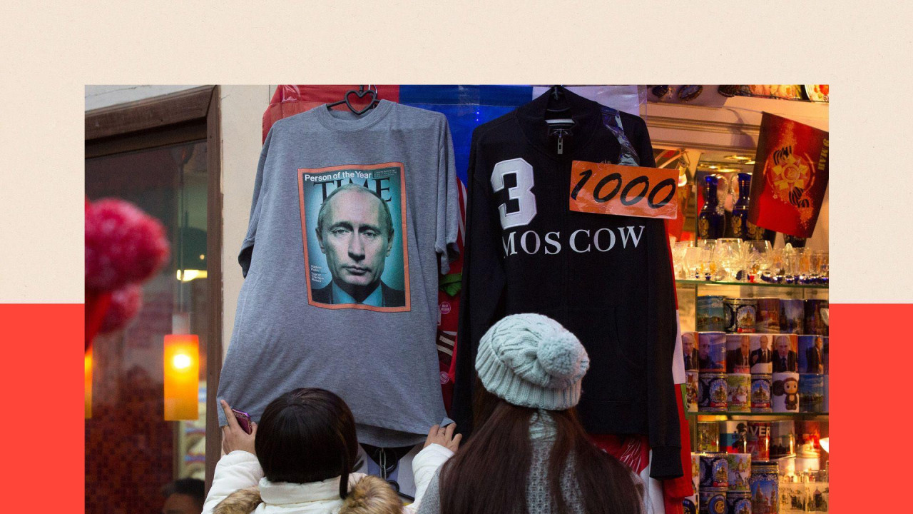 Dve žene okrenute leđima gledaju u majicu na kojoj Putinova slika za časopis Tajm u prodavnici suvenira