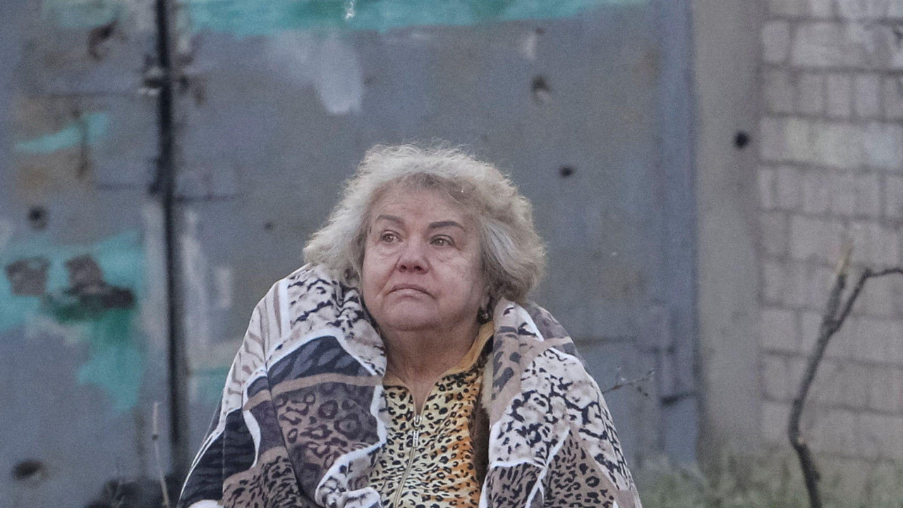 napad na ukrajinu, žena umotana u ćebe stoji na travi posle ruskog napada na dnjepar