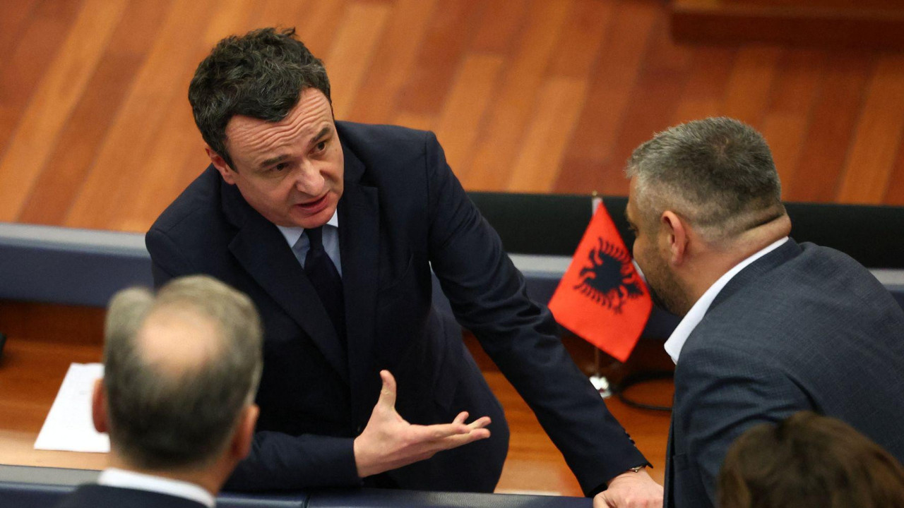 Aljbin Kurti u tamnom odelu razgovara sa dvojicom muškaraca