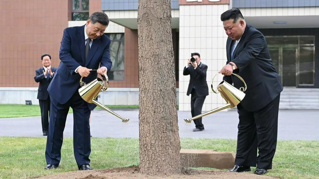 Si u plavom odelu i Kim u crnom  zlatnim kanticama zalivaju drvo