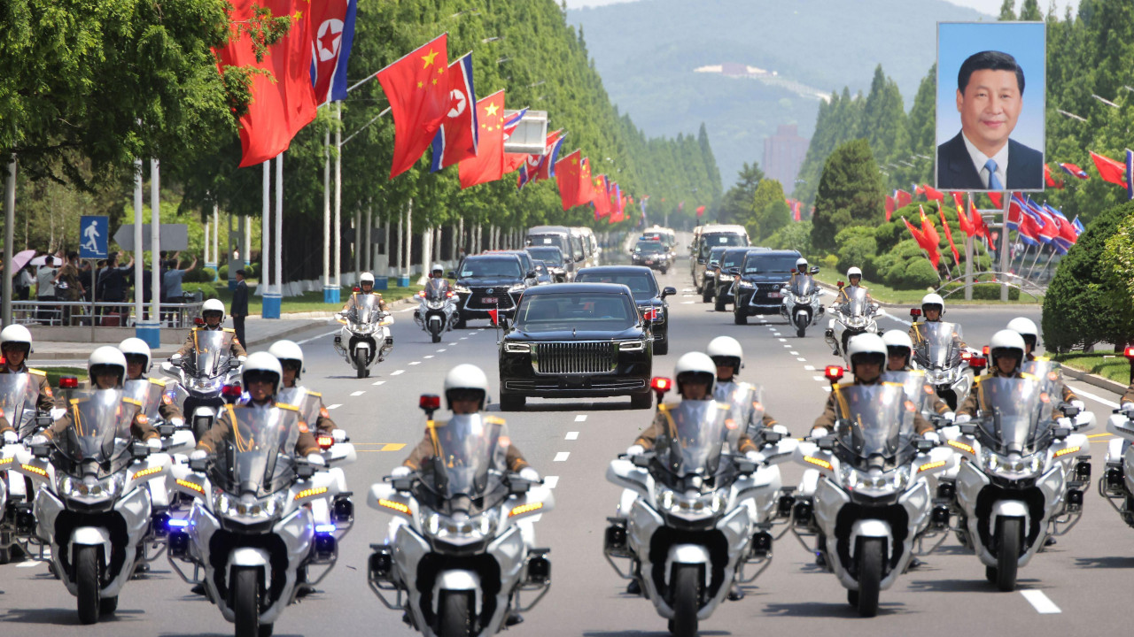 Desetine motociklista ispred nekolicine crnih automobila na jednoj od bandera slika kinekog predsednika Sija Đinpinga