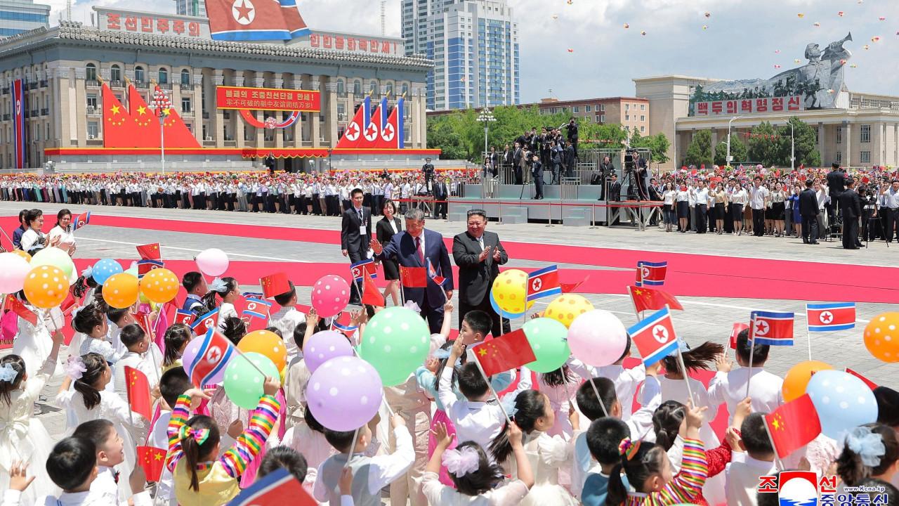 Desetine dece pored crvenog tepiha maše balonima i zastavama Severne Koreje
