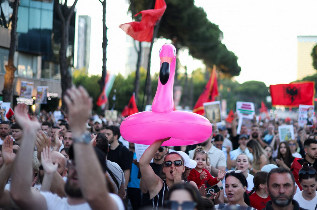Devojka drži šlauf u obliku flamingosa na protestu okružena ljudima