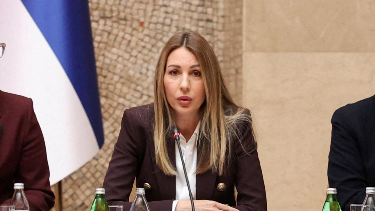 Žena u sakou priča u mikrofon