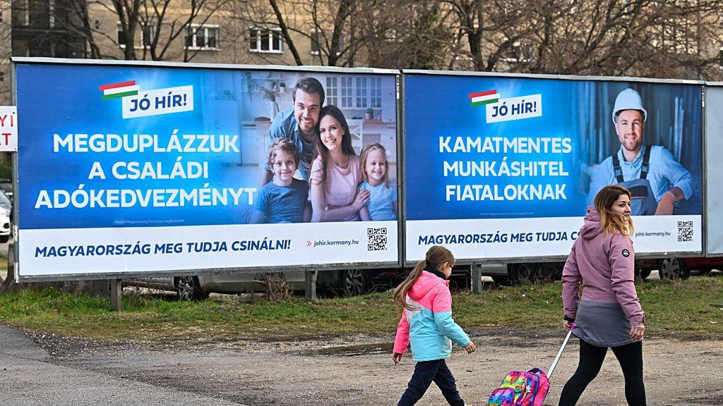 Majka prolazi sa ćerkom pored bilborda na kojima se reklamira populaciona politika države