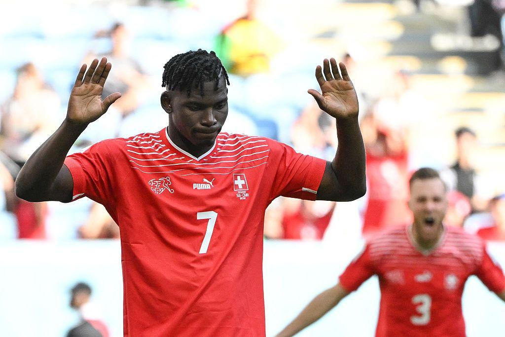 
                    Breel Embolo of Switzerland, wearing a red shirt with the number seven on it, raises his arms after scoring against Cameroon, his country of birth, in the 2022 World Cup
                