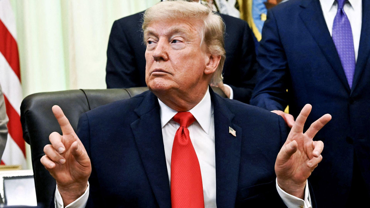 Donald Tramp u teget odelu sa crvenom kravatom podignutih ruku