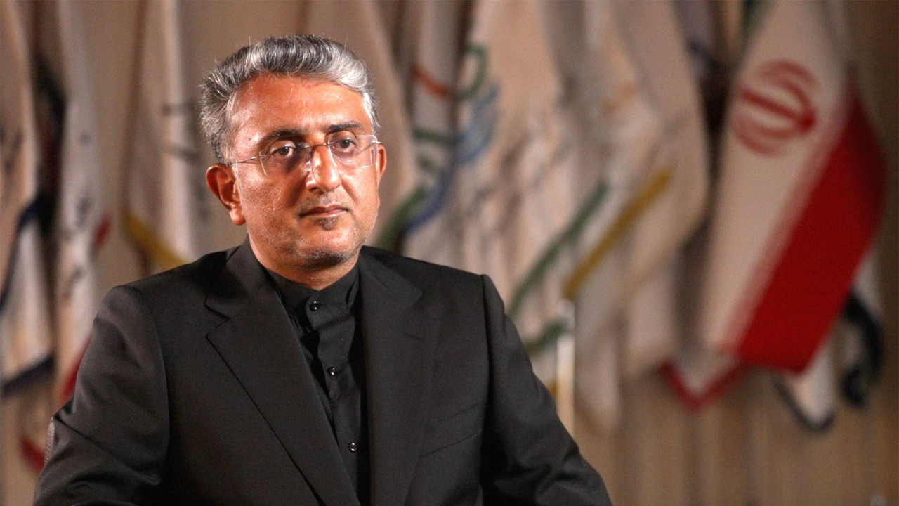 Mehdi Nobani, gradonačelnik Bandar Abasa, u crnom odelu i crnoj košulji, sedi dok se iza njega vidi iranska zastava