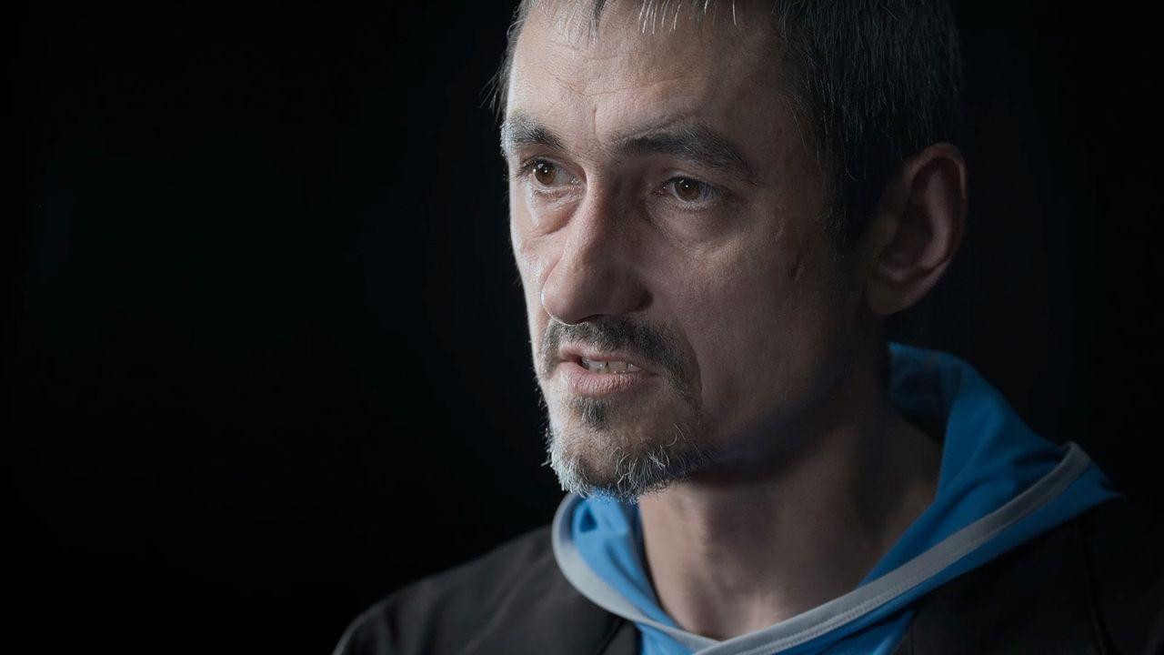 Muškarac gleda u stranu u crnoj jakni ispod koje proviruje plavi duks
