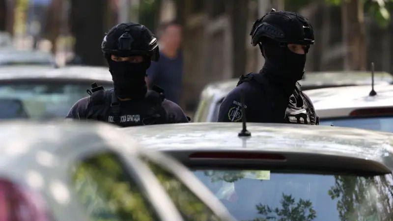 Dvojica policajaca u punoj opremi ispred automobila