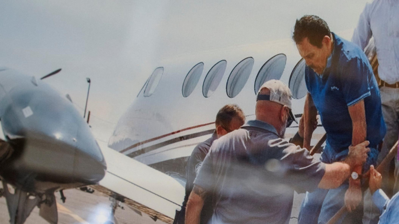 Zambadi, obučenom u plavu majicu za golf, pomažu da izađe iz malog aviona dok ga privode u julu 2024.