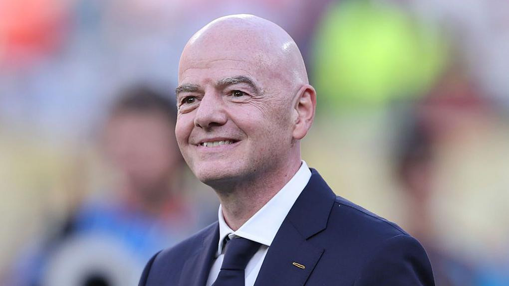 Head and shoulders of a smiling Gianni Infantino, wearing a dark suit and tie