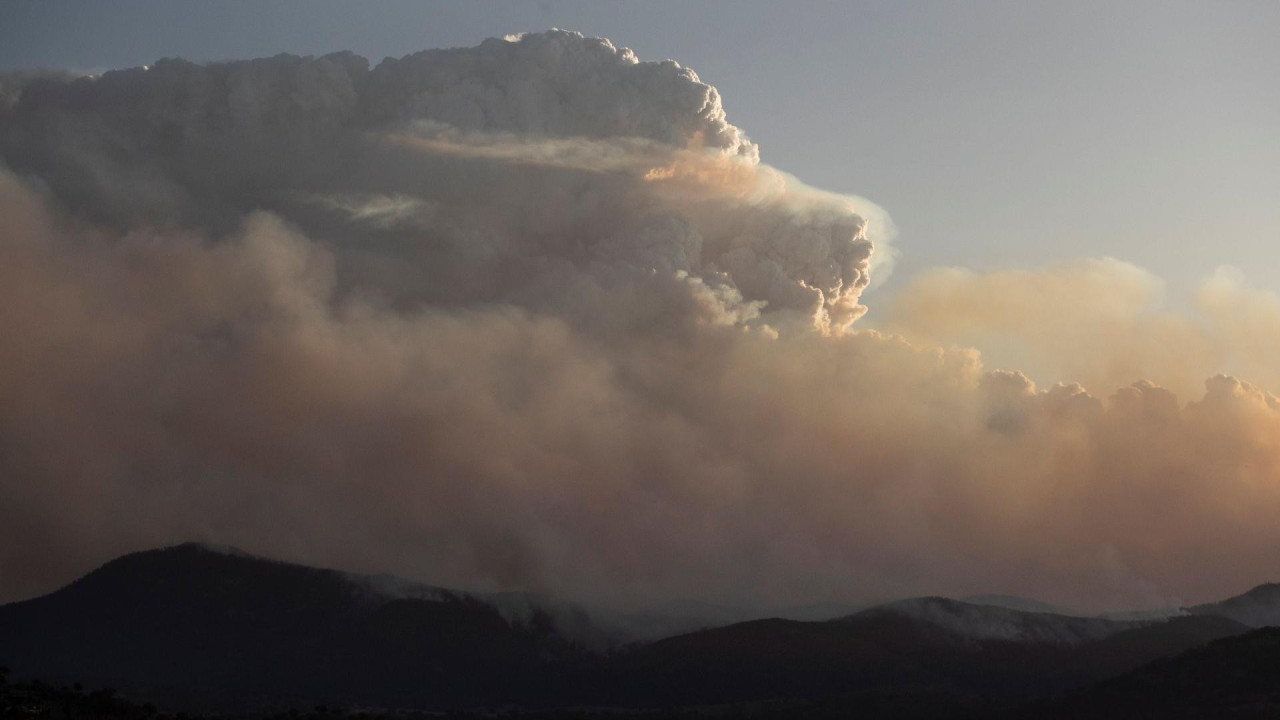 Veliki oblak iznad tamnih brda sa dimom koji okružuje region