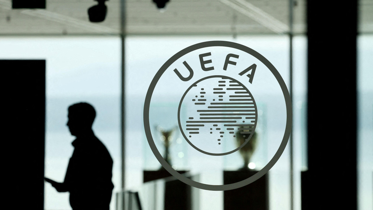 Silueta muškarca u pozadini, vidi se kroz staklo, napred logo UEFA na staklenim vratima