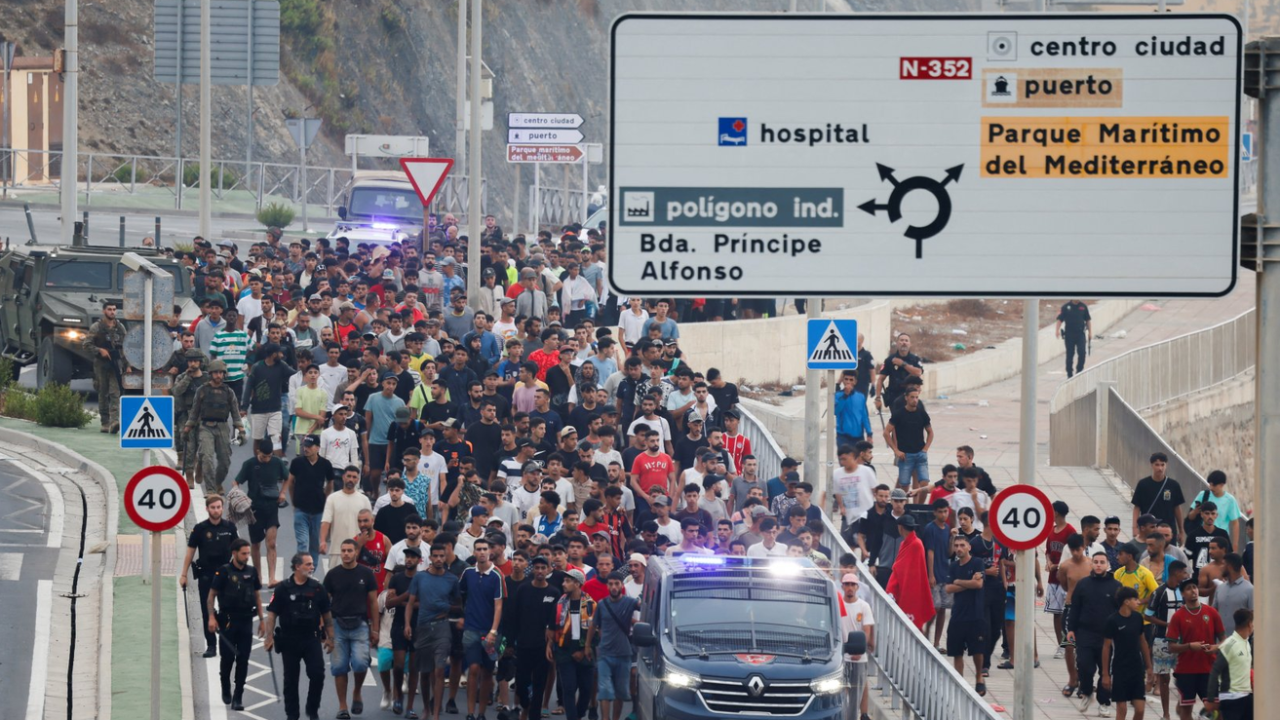 Grupa ljudi ide ulicom oko njih su policijska kola i policajci koji idu peške