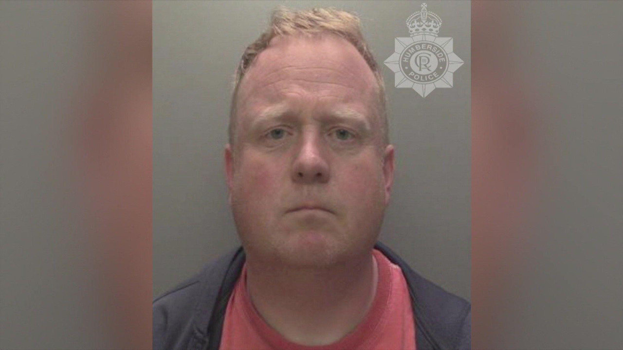 Undertaker Robert Bush stares at the camera in a police mugshot. He has a neutral expression, his mouth slightly down-turned and a faint frown.