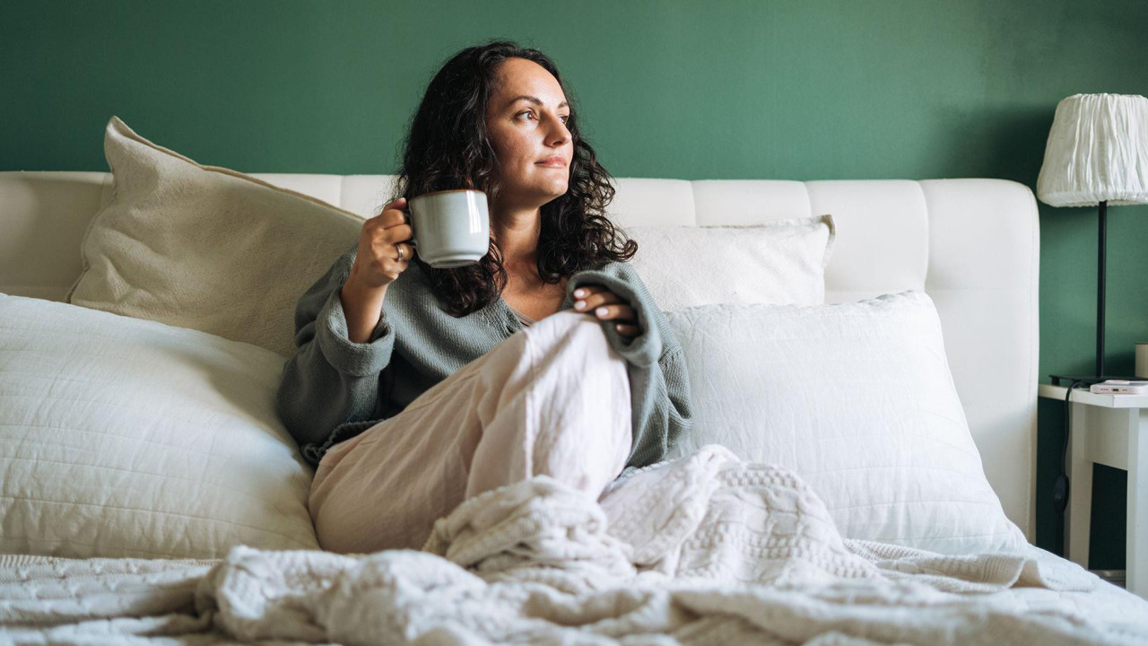 A woman in bed drinking a cup of tea