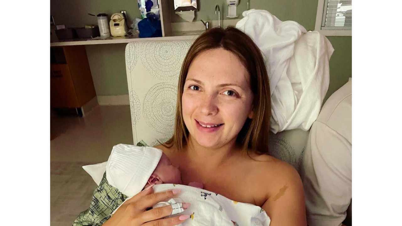 Žena leži u bolničkom krevetu i drži bebu na grudima
