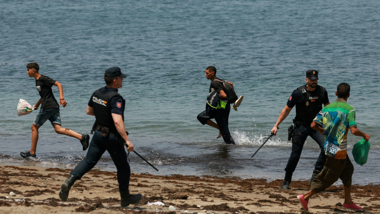 španska policija juri migrante po plaži u seuti