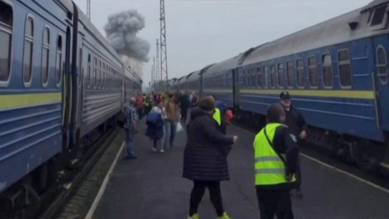 passengers leave train as smoke from explosion visible in background