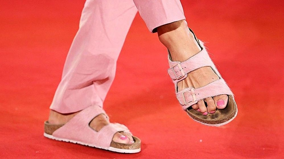 žena u roze sandalama kompanije birkenstok i roze pantalonama, ima roze lak za nokte na nogama