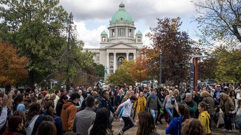 pristalice studentske liste igraju kolo, u pozadini je zgrada skupštine srbije
