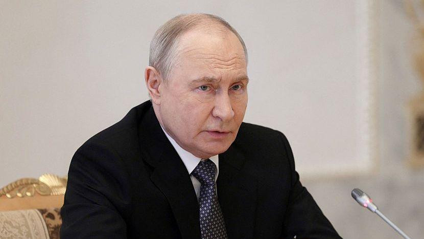 Vladimir Putin govori u mikrofon, ima tamno odelo, belu košulju i tačkastu tamnu kravatu