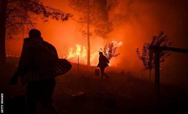 Seljani nose kofe sa vodom da bi pokušali da ugase vatru blizu svojih domova u Makau, južno od Tondele, u julu 2019. godine