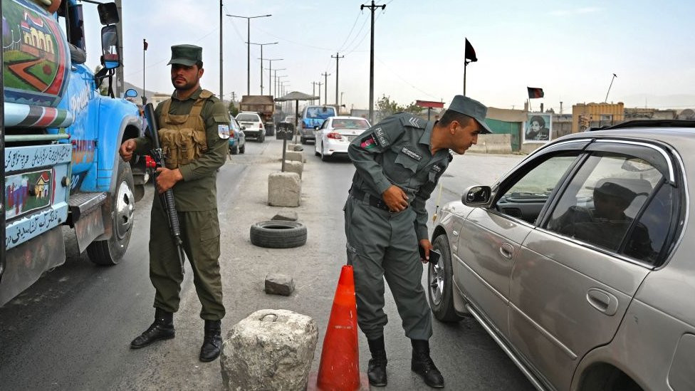 Afghan police stand guard at a checkpoint along the road in Kabul on August 14, 2021