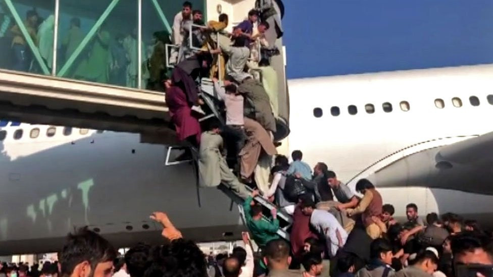 People attempting to climb onto a plane at Kabul airport