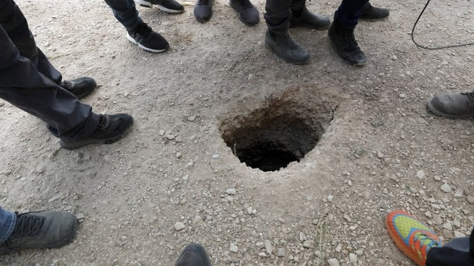 Policajci i novinari okupljeni oko ulaza u tunel koji su zatvorenici iskoristili da pobegnu iz zatvora Gilboa
