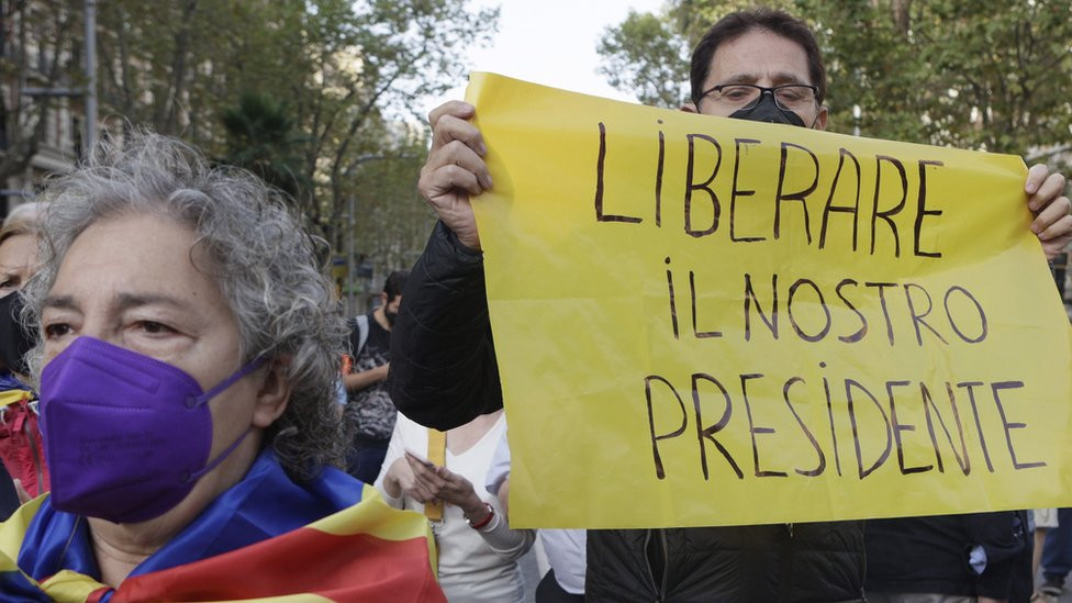 A demonstrator holds a banner reading in Italian language "Free Our President" as several dozens people rally in front of Italian Consulate