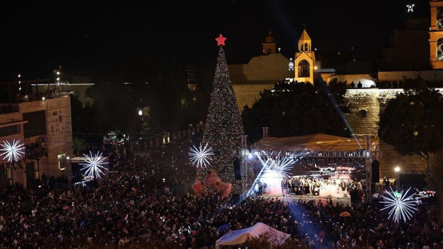 Vitlejem noćni pogled na osvetljeni trg sa velikom jelkom i crvenom zvezdom na vrhu