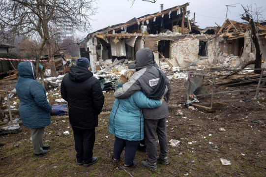Ljudi zagrljeni gledaju porušenu kuću posle napada u regionu Kijeva